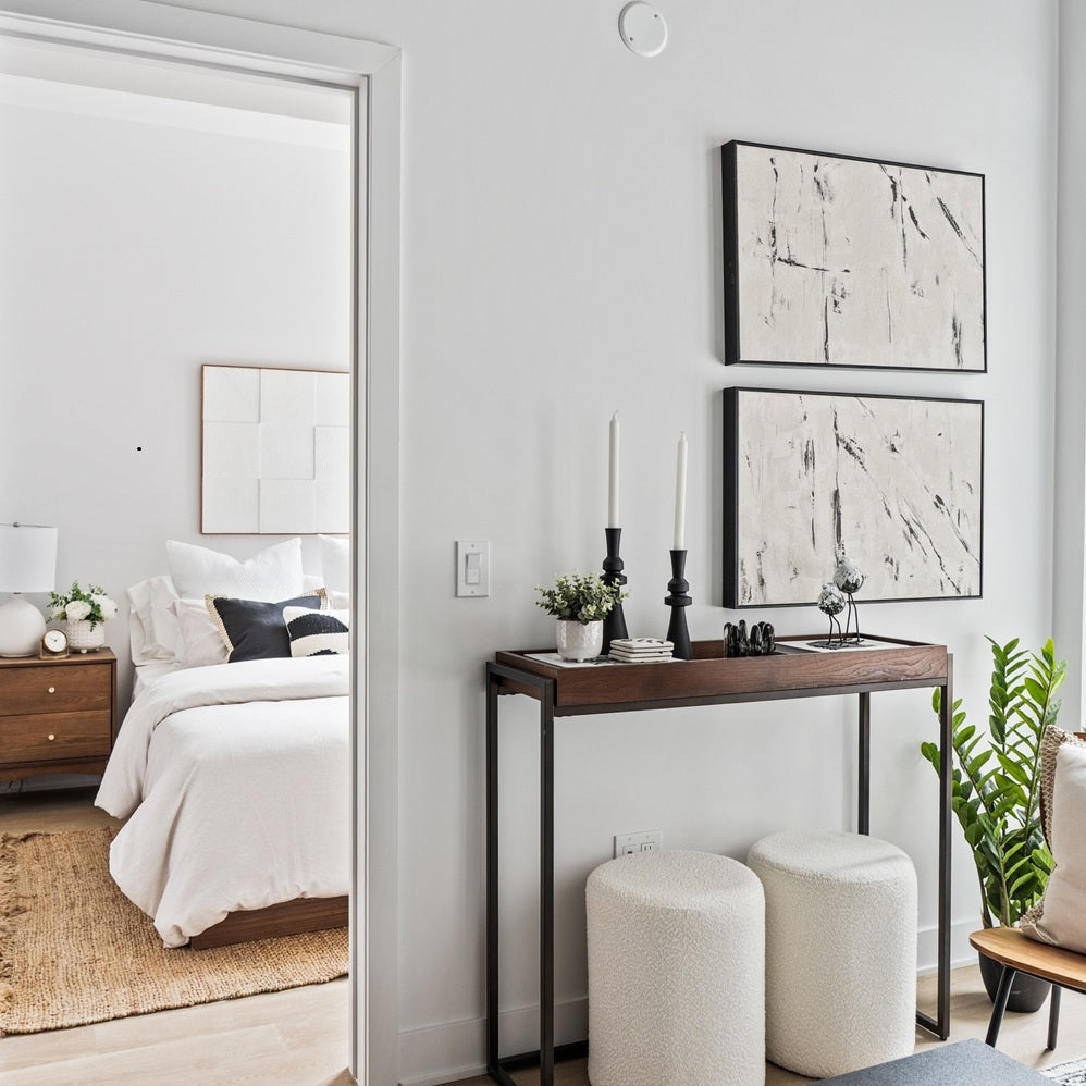 Modern apartment design with contemporary white bedroom with warm neutral tones and console table styled with abstract art and decorative items