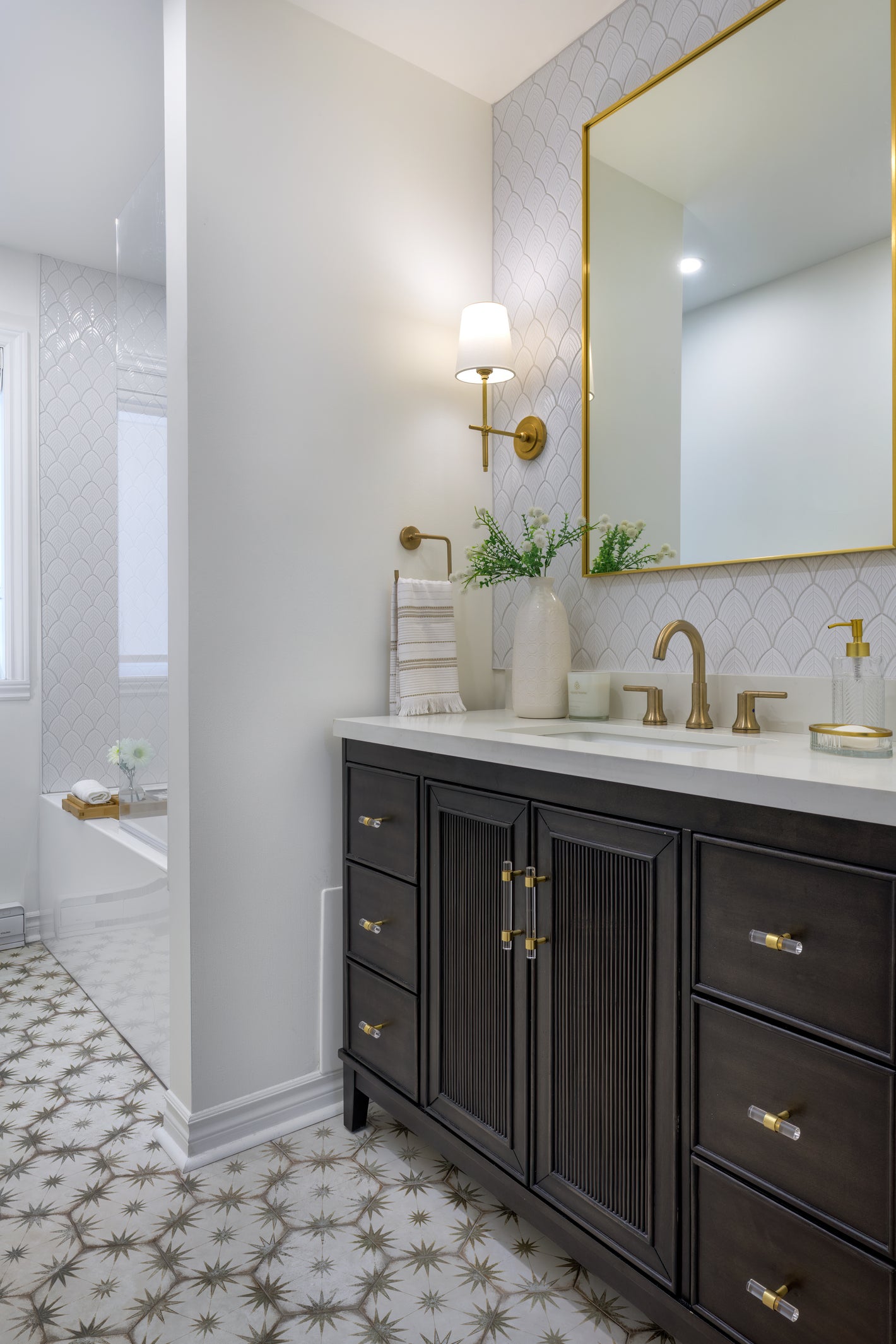 Bathroom with dark vanity, white countertop, gold fixtures, and patterned floor tile.