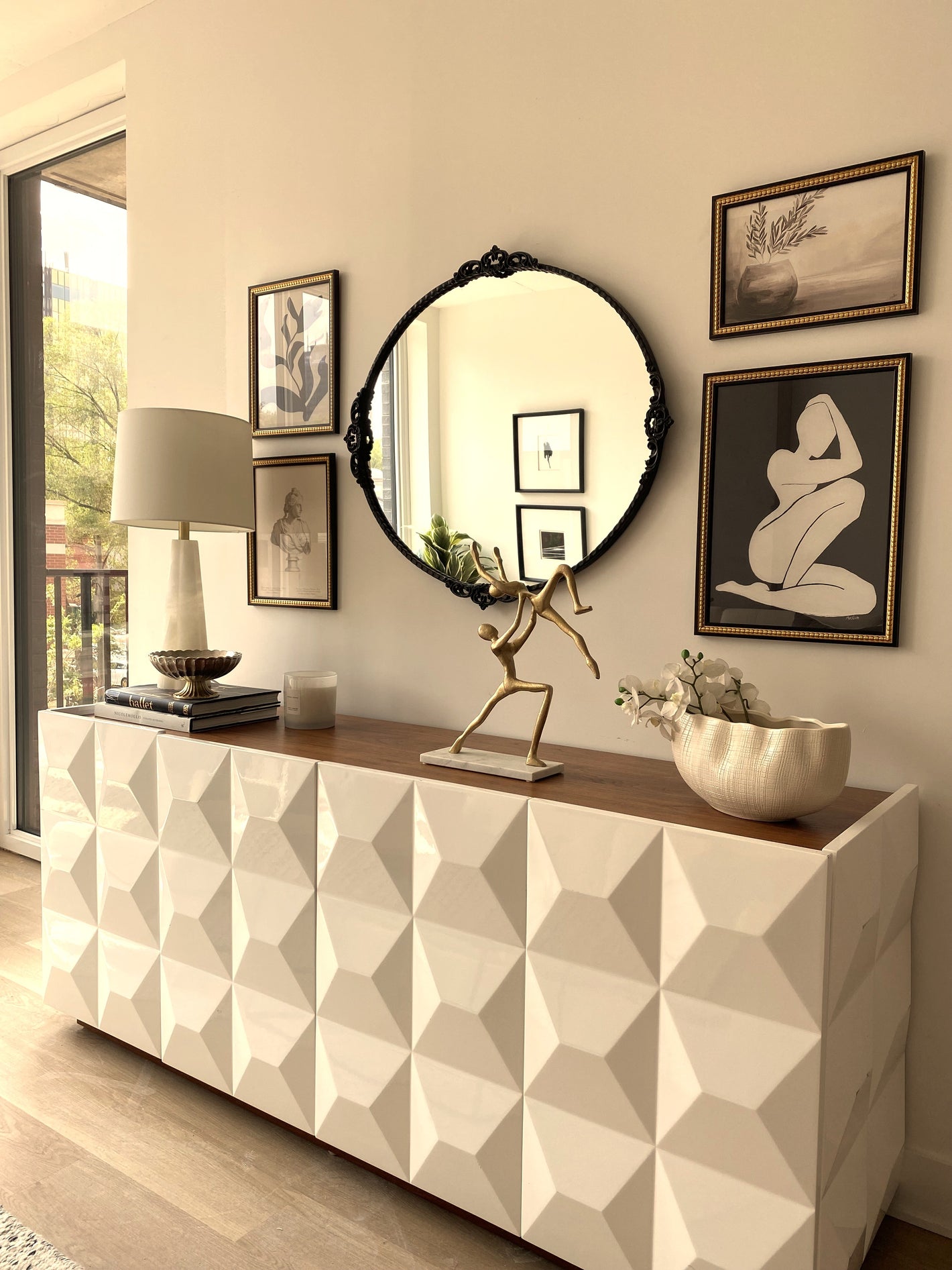 Modern interior design with a geometric-pattern sideboard, round mirror, and framed vintage art.